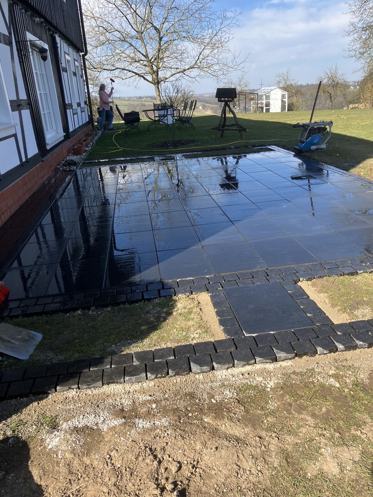 Große Terrassenfläche mit dunklen Feinsteinzeugplatten direkt am Wohnhaus